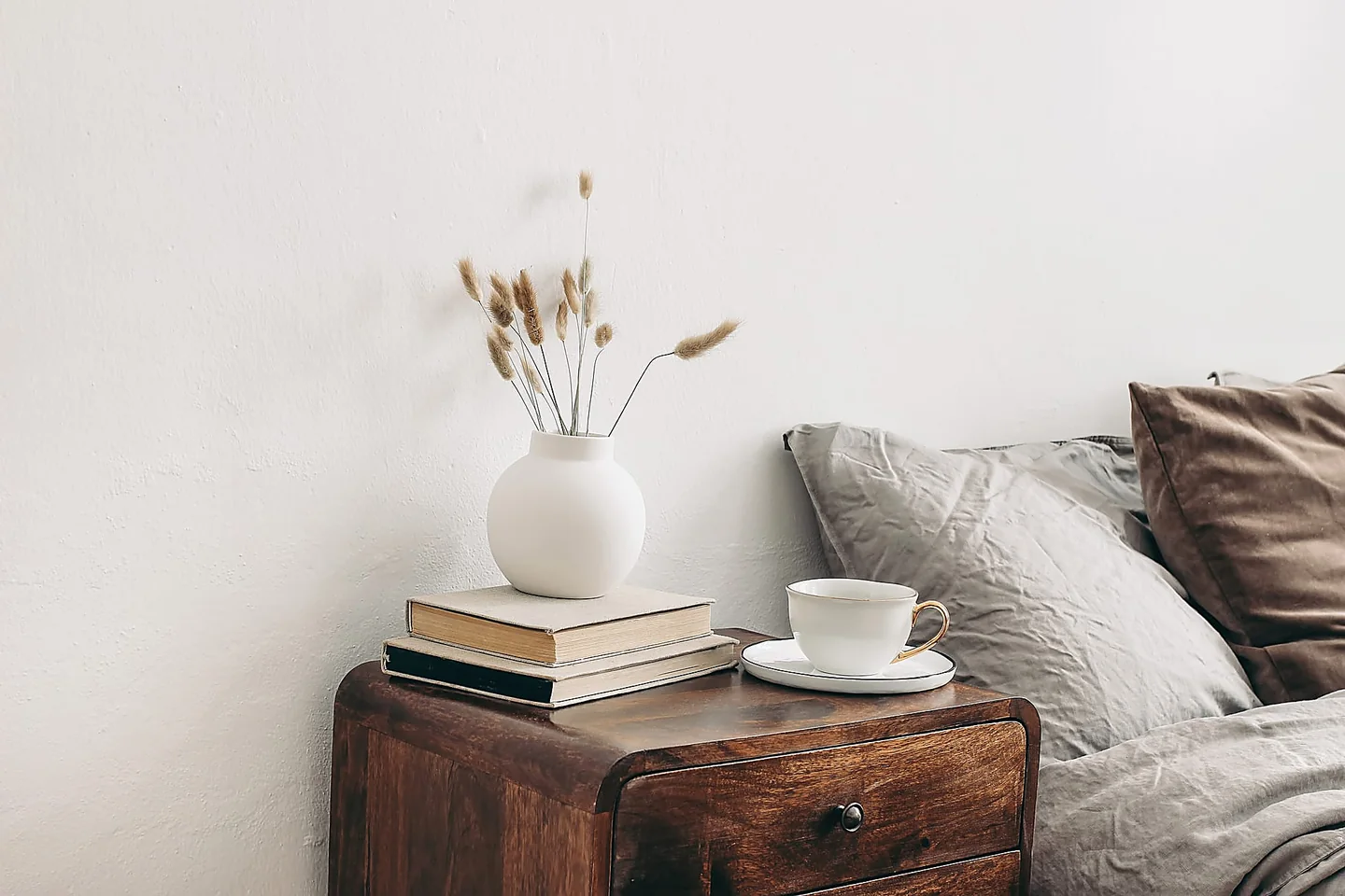 Ambiente valorizzato con home staging: comodino in legno, tessuti chiari e dettagli curati